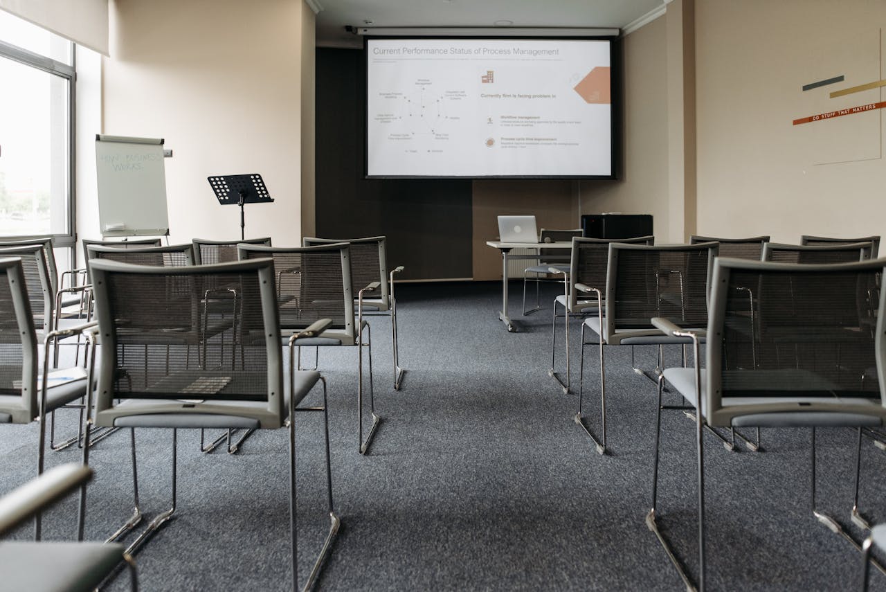 An empty conference room with chairs, a projector screen, and presentation setup.